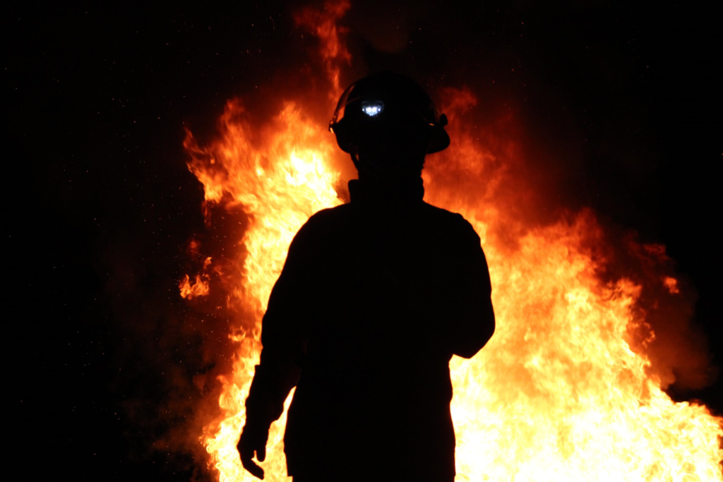 a firefighter standing with fire in the back