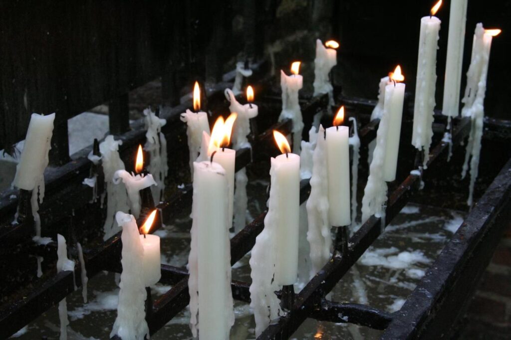 A collection of melting candles with flickering flames. 