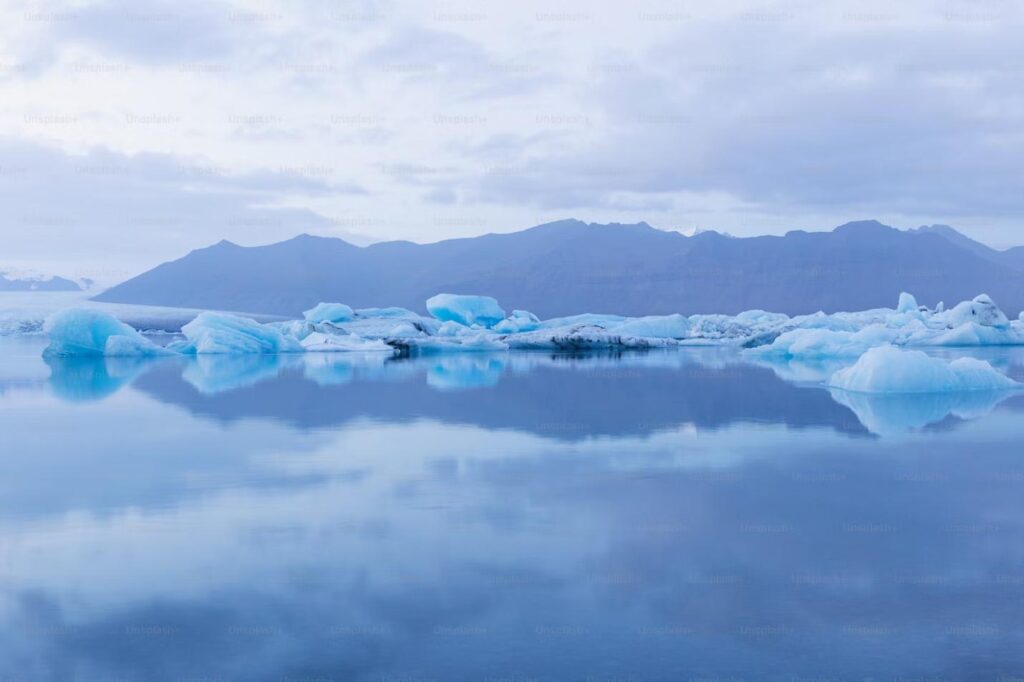 A peaceful icy landscape with floating icebergs and distant mountains