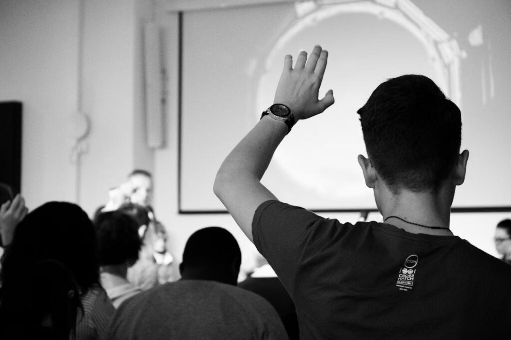 A student raising their hand in a group discussion.